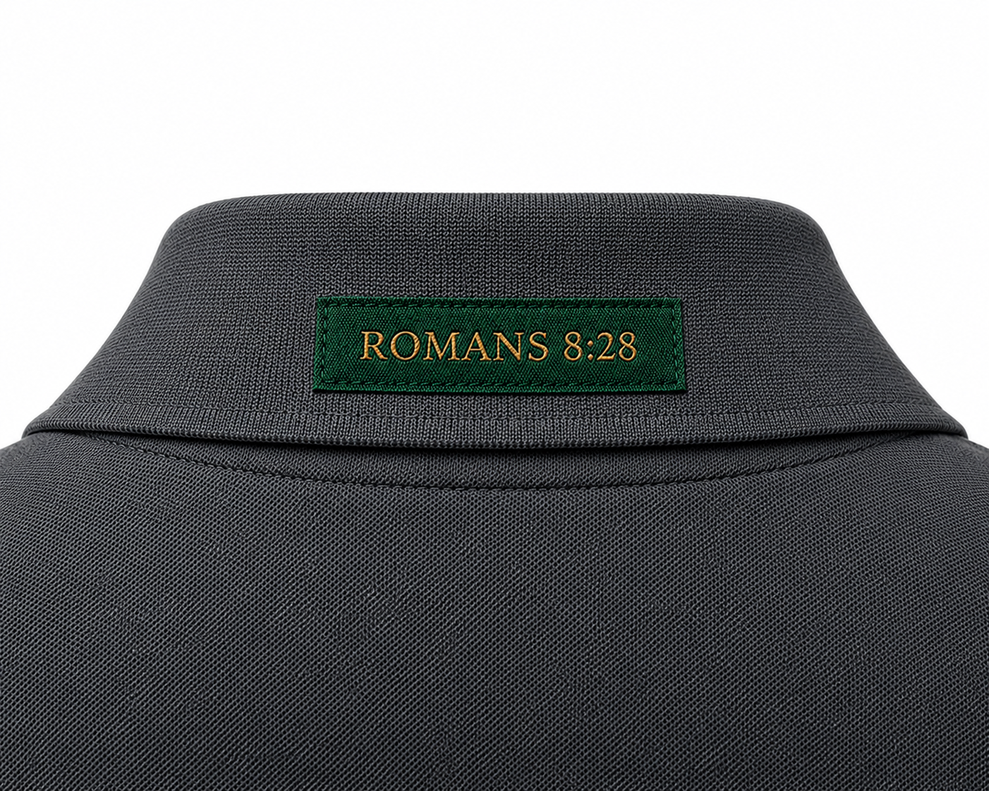The Verse Polo™ in Graphite — back collar detail showing the Ordinary green verse patch, Romans 8:28